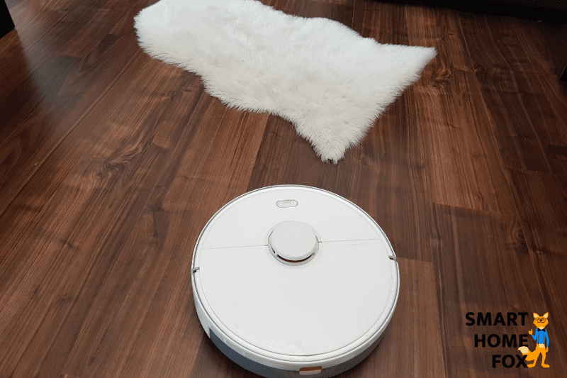 Man sieht, wie ein Saug-Wischroboter den Parkettboden feucht absaugt.